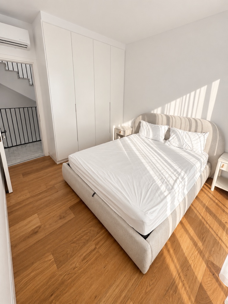 Bedroom with upholstered bed, fitted white wardrobes and sunlight at Harmony Residence Villa 12