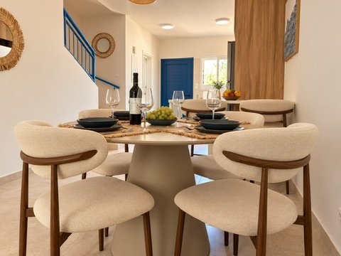 Round dining table set with wine glasses beside the blue front door at Paradise Gardens Villa 30