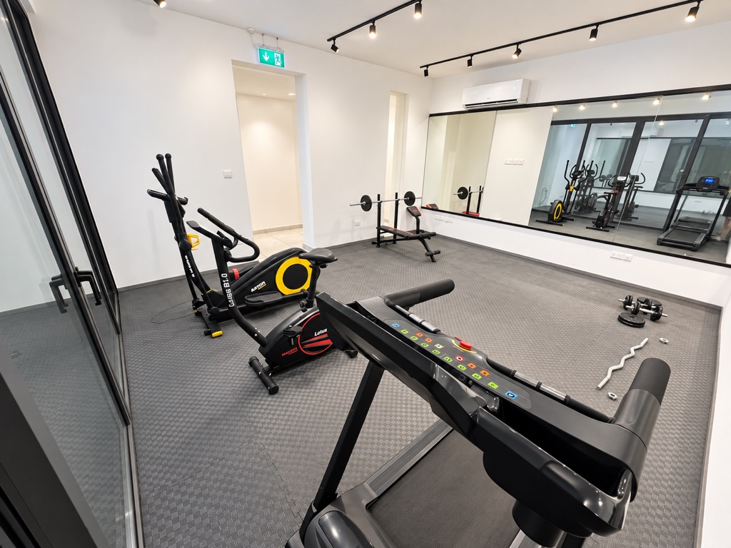Bright gym with cardio equipment, weights and mirrored wall at Stay City 301