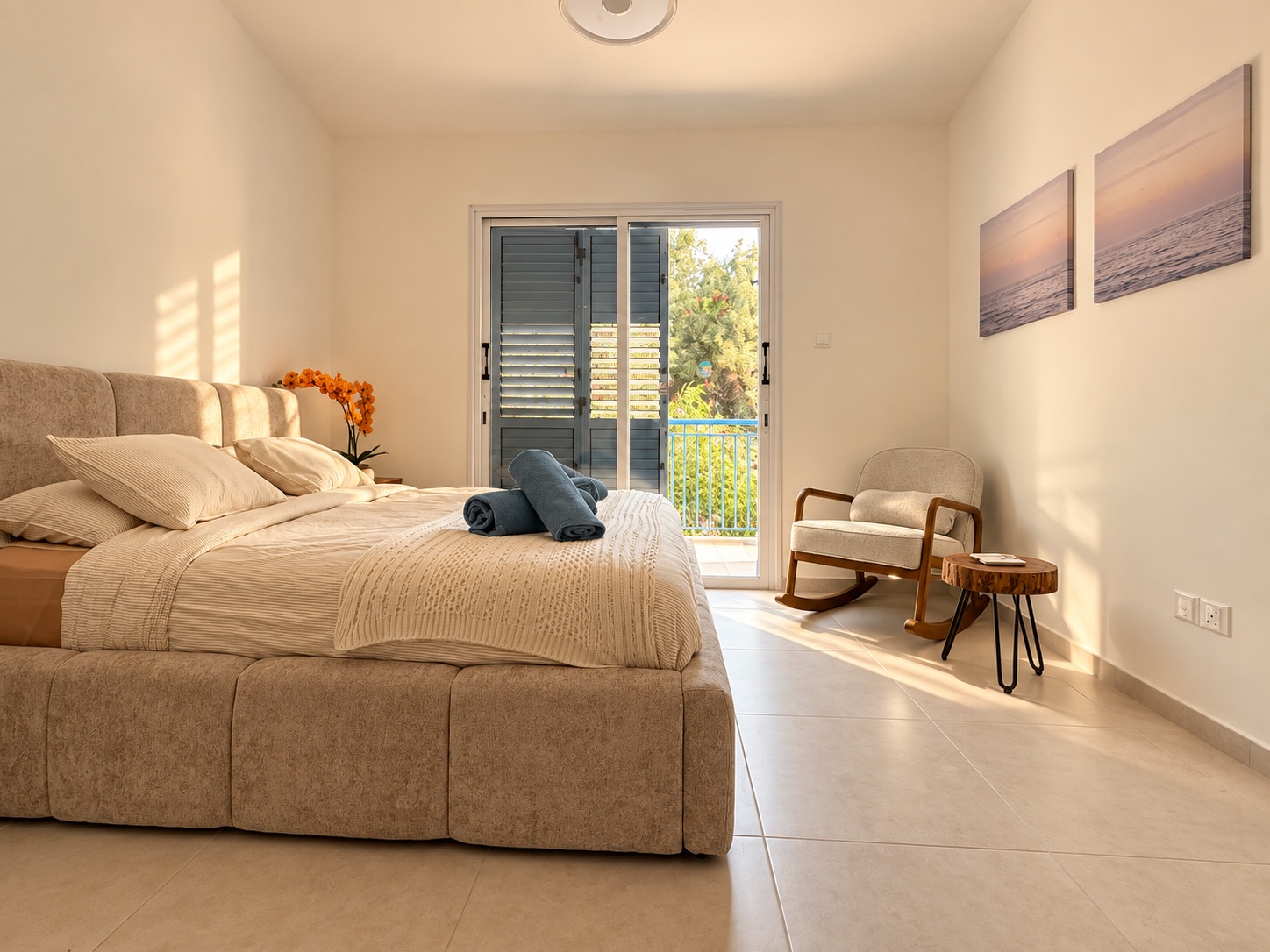 Sunny main bedroom with upholstered bed, armchair and balcony doors at Paradise Gardens Villa 30
