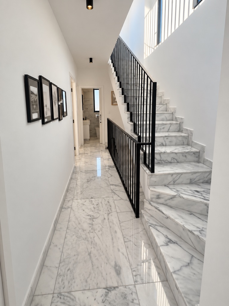 Bright double-height staircase hall with marble stairs, black railings and a hallway leading through Harmony Residence Villa 12
