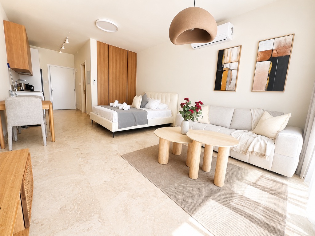 Alternative view of the open-plan studio with kitchen, sofa and bed at Avalon Gardens A008