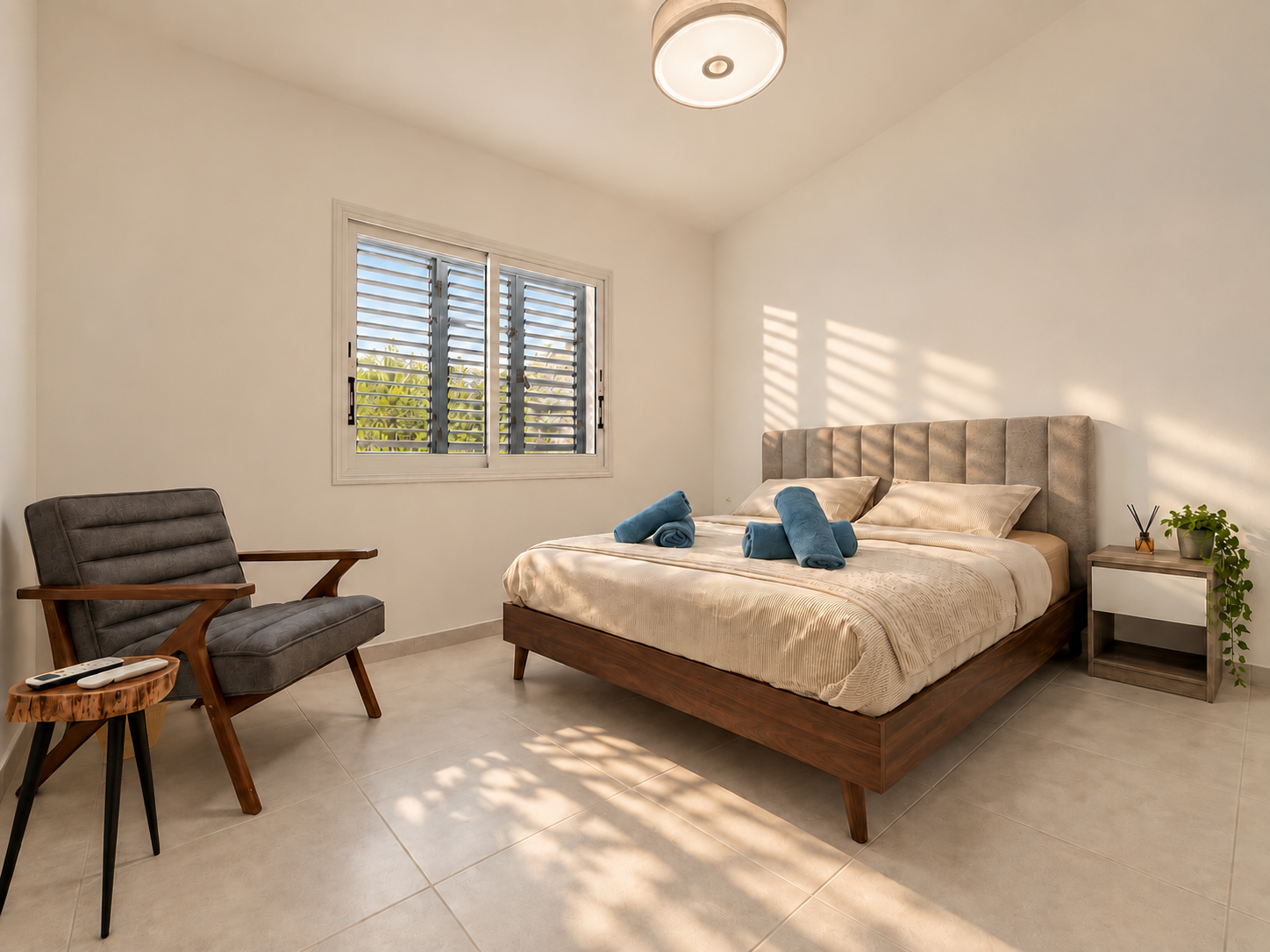 Second bedroom with wooden bed base, upholstered headboard and armchair at Paradise Gardens Villa 30