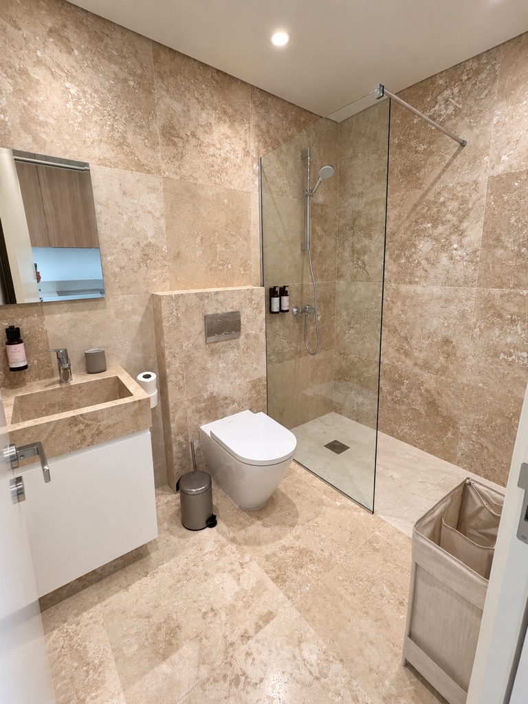 Avalon Gardens A007 stone-finished bathroom with walk-in shower, WC and vanity